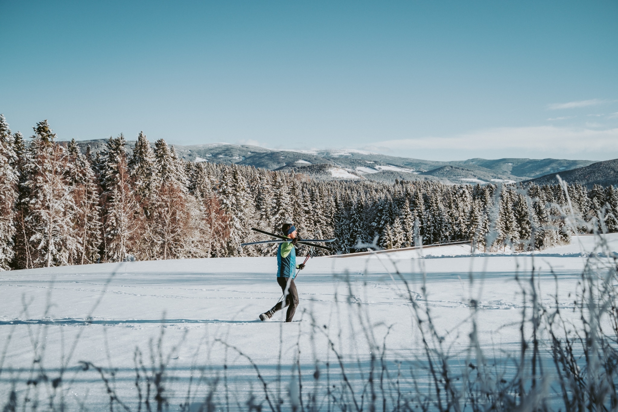 hfast50_winter_cmvisuals Langläufer trägt die Langlaufski durch verschneite Landschaft im Joglland in der Oststeiermark